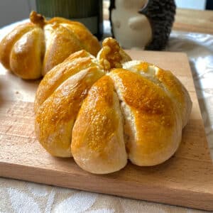 Twee pompoenbroodjes op een snijplank op tafel